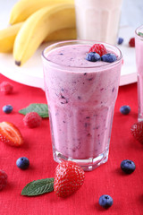 Milkshakes with berries at red textile on light background