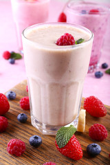 Milkshakes at cutting board with berries on light background, close-up