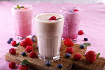 Milkshakes at cutting board with berries on light background