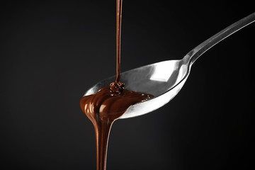 Chocolate poured on a spoon on dark background
