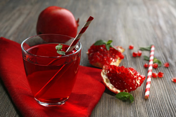 A glass of tasty juice and garnet fruit, on wooden background