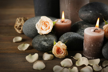 Fototapeta na wymiar Beautiful relax composition of alight candles, pebbles and flowers on wooden background
