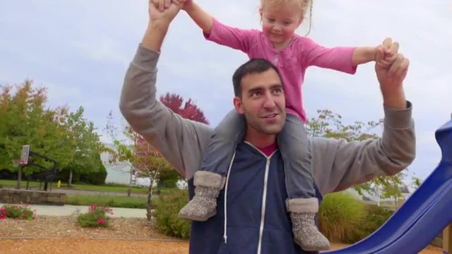 Cute little girl pretends to fly on top of her fathers shoulders 