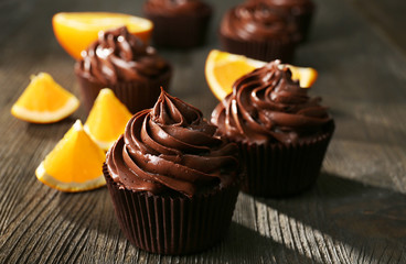 Chocolate cupcakes and cut orange on wooden table