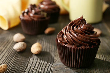 Chocolate cupcakes served with a drink and nuts on wooden table