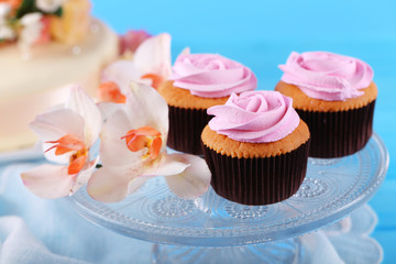 Tasty cupcakes on stand and cake, on table, on color background