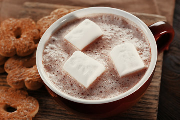 Cup of hot cacao with cookies and nuts on wooden kitchen board, close up