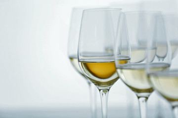 Wineglasses with white wine on wooden table on bright background