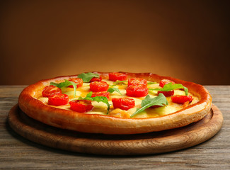 Pizza Margherita with arugula on brown background