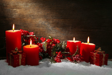 Burning candles, rowan and gift box with snow on wooden background
