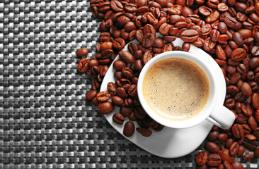 Naklejka premium Cup of coffee and coffee grains on dark background