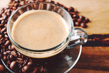 Cup of coffee and coffee grains on wooden table background