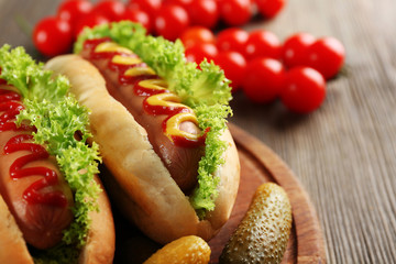 Tasty hot-dogs with vegetables on wooden table