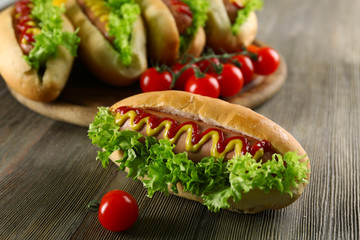Tasty hot-dog with tomatoes on wooden table