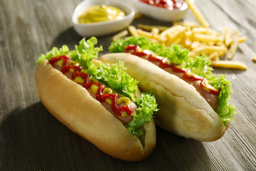 Tasty hot-dogs with French fries on wooden background, close up
