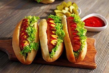 Delicious hot-dogs on wooden chopping board
