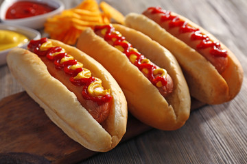 Tasty hot-dogs with chips on wooden background