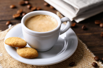 Cup of coffee, cookie and newspaper on wooden table background