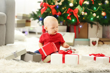 Obraz na płótnie Canvas Funny baby with gift boxes and Christmas tree on background