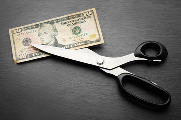 Concept of spending money - scissors cut money on black background