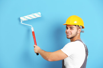 Young worker renewing apartment on wall background