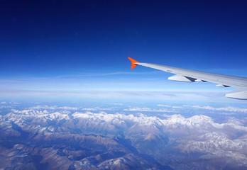Fototapeta na wymiar Looking though plane window to the Alps valley