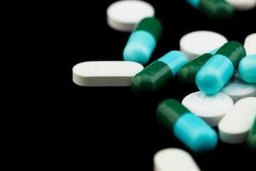 Pharmaceutical medicament, cure in container for health. Antibiotic, painkiller closeup. Medicine pills or capsules over black color background.