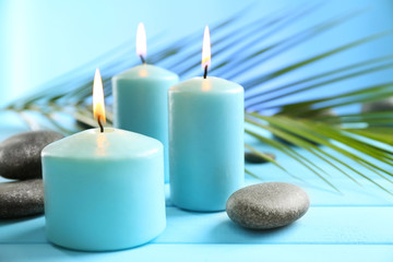 Spa composition of blue candles, stones on blue background