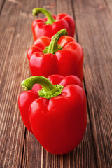 Three red peppers on a wooden background view