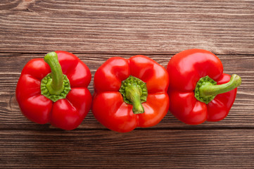 Three red peppers on a wooden background. Top view