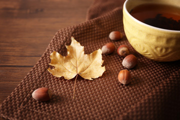 Cup of tea with autumn decor on wooden table.