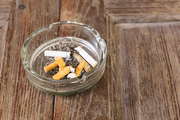 Closeup view of full ashtray on the wood  table
