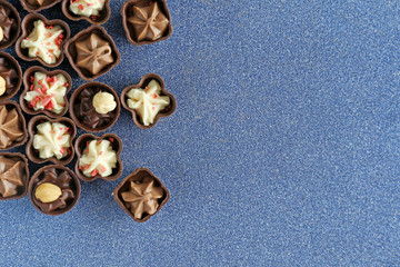 Delicious chocolate candies on blue background, close up