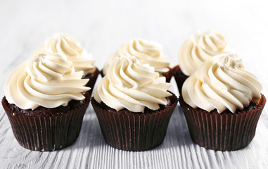 Tasty cupcakes on white wooden background, close up