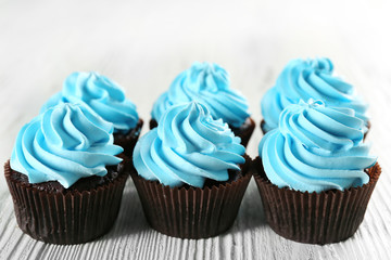 Delicious cupcakes on white wooden background, close up