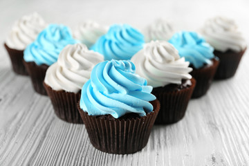 Fresh delicious cupcakes in a row on white wooden  background