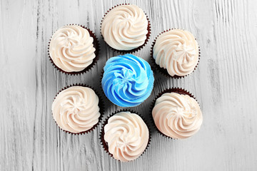 Tasty colourful cupcakes in a row on white wooden  background