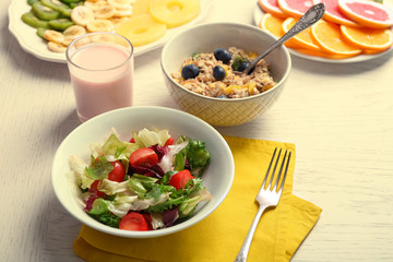 Tasty oatmeal and vegetable salad on wooden background. Healthy eating concept.