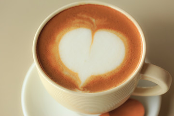 Heart shape in hot cappuccino coffee cup on white desk