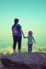 Mother and daughter standing on boulder and clasping hand together