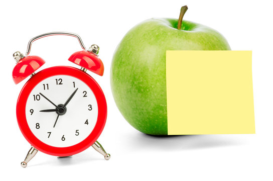 Fresh apple with alarm clock and sticker