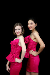 two women in pink dresses on black