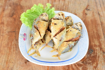 Fried mackerel in dish on wood table.