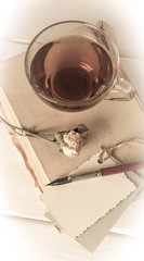 Old book with decorative  card, dried roses, nib pen and cup tea