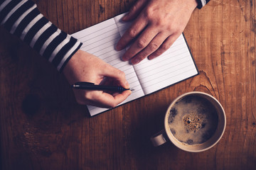 Fototapeta na wymiar Woman drinking coffee and writing a diary note