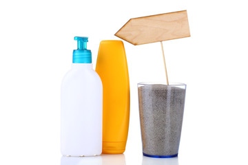 wooden pointer in a glass with sand and a bottle of shampoo on white background isolated