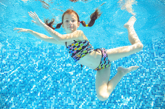 Girl jumps, dives and swims in pool underwater, happy active child has fun under water
