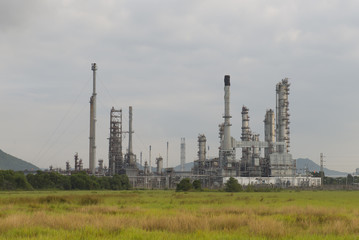 Fototapeta na wymiar Oil refinery among grass