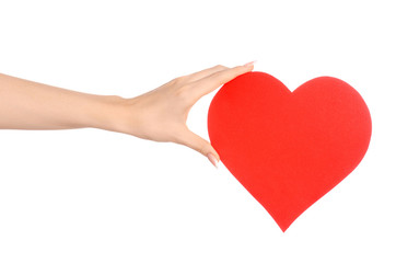 Love and greetings card theme: beautiful female hand holding a paper card red heart isolated on a white background in studio