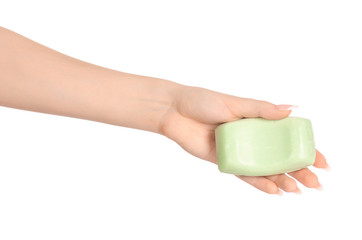 Hygiene and health care topic: a woman's hand holding a green bar of soap isolated on white background in studio